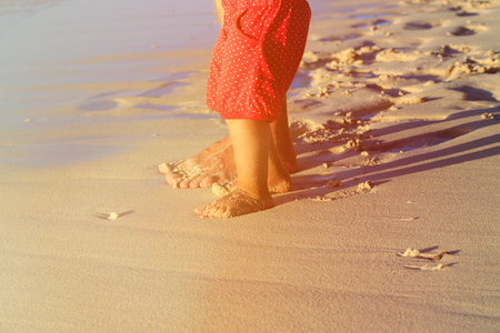 Close up of father and little daughter feet on beach, family vacationの写真素材