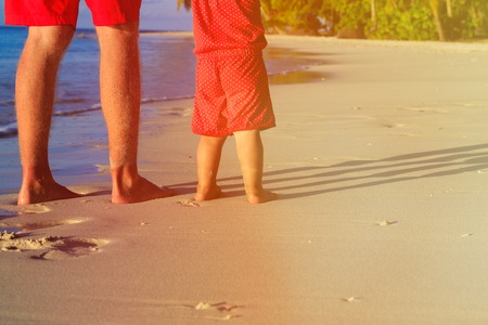 Close up of father and little daughter feet on beach, family vacationの写真素材