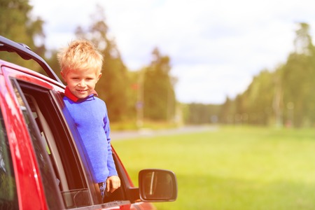 happy little boy travel by car in summer nature