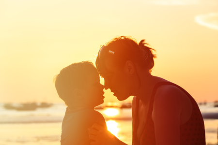 happy loving mother and little son at sunset beachの写真素材