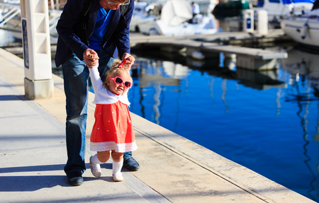 family travel concept- father and little daughter learning to walk in portの写真素材