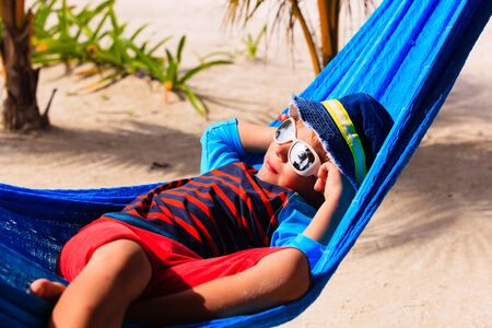 happy little boy relaxed in hammock on beach, family vacationの写真素材