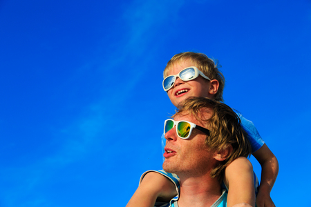 Father and little son playing on blue summer skyの写真素材