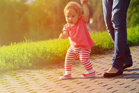 first steps of little girl with mother in summer