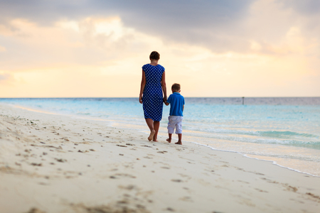 mother and little son walking on sunset beachの写真素材