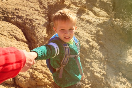 Helping hand- little boy helped by parent in mountainsの写真素材