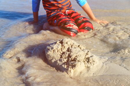 little boy play with sand and water on beachの写真素材