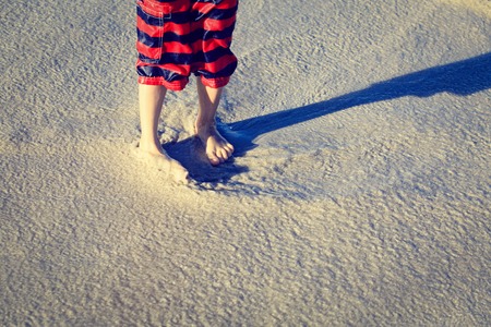 Feet of a child on the sand beachの写真素材
