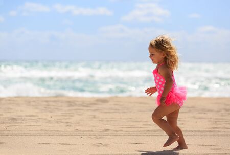 little girl run on sand beach, family vacationの写真素材