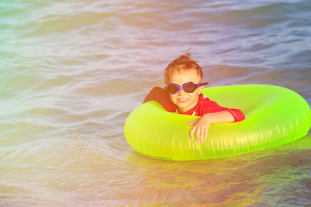 happy little boy with life ring has fun on beachの写真素材