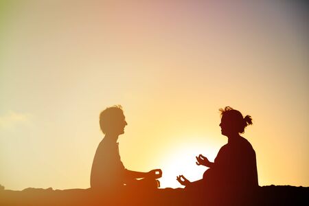 silhouette of couple doing yoga at sunset skyの写真素材