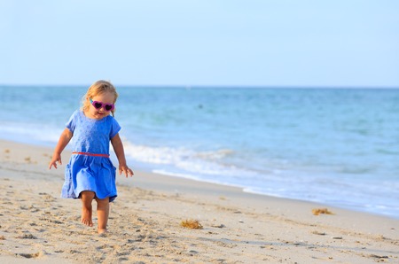 happy cute little girl run on sand beachの写真素材