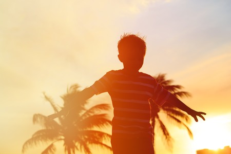 Silhouette of happy little boy play at sunset beachの写真素材