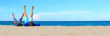father and little son play on sand beach, panoramaの写真素材