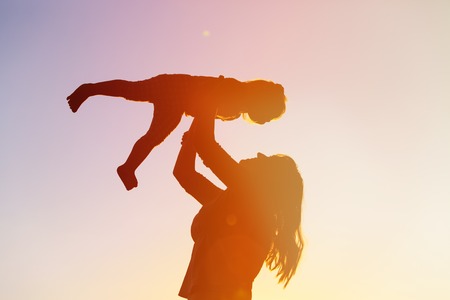 silhouette of mother and little daughter play at sunsetの写真素材