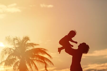 Father and little daughter play silhouettes at sunset skyの写真素材