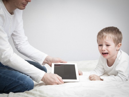 computer addiction, parent taking out touch pad from crying childの写真素材