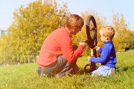 father and son fixing bike in autumn natureの写真素材