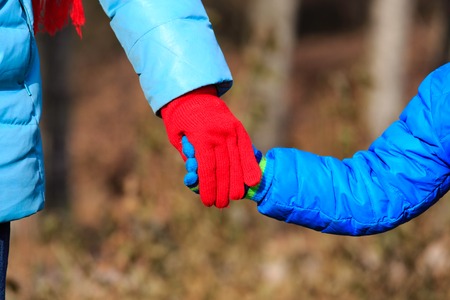 Mother holding hand of her little son in autumn natureの写真素材