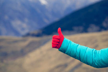 Woman hand with thumb up in mountains. Love mountains travel conceptの写真素材