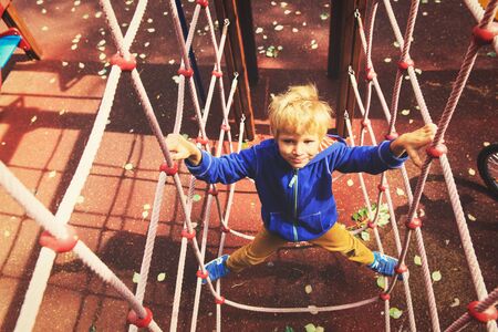 little boy climbing on the web in playground, kids sportの写真素材