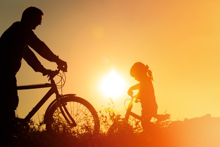 father and little daughter having fun riding bike at sunset, active family sportの写真素材