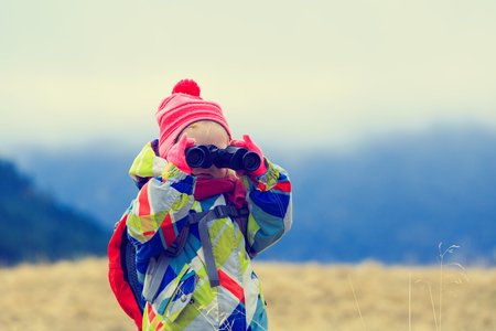family travel- cute little girl with binoculars exploring winter mountainsの写真素材