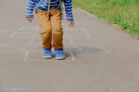 little boy playing hopscotch on playground outdoorsの写真素材