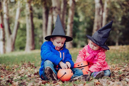 little boy and girl in halloween costume play at autumn, kids trick or treatingの写真素材