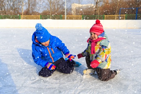 happy little boy and girl skating together, kids winter sportの写真素材