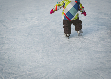 little girl learning to skate on ice in winter snowの写真素材
