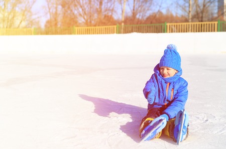 cute little boy learning to skate in winter snowの写真素材