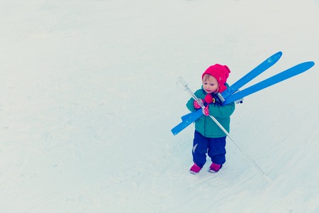 little girl bringing ski in winter snow, kids winter sportの写真素材