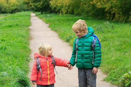 kids go to school - brother and sister with backpacks walking on the roadの写真素材