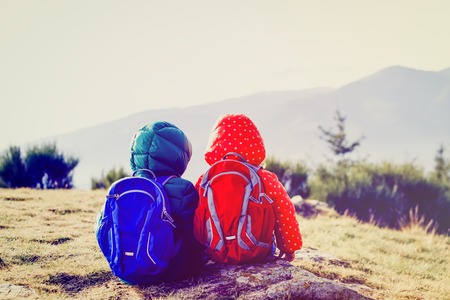 family travel concept - little boy and girl hiking in mountainsの写真素材