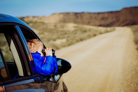 cute little boy travel by car on road to mountainsの写真素材