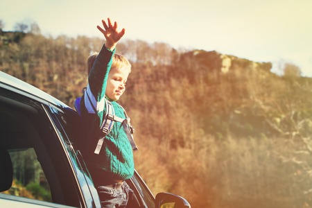 happy little boy travel by car in autumn nature