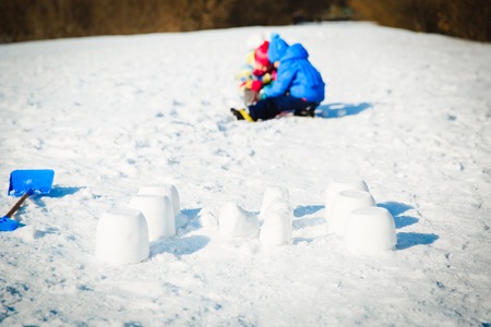kids play in winter snow- little boy and girl building snowcastleの写真素材