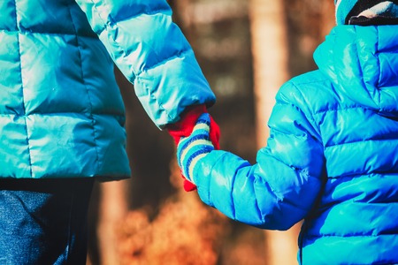 Mother holding hand of her son in autumn fallの写真素材
