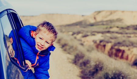 happy little boy travel by car on road to mountains, family travelの写真素材