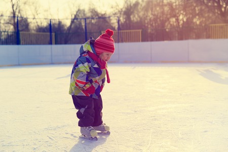 cute little girl learning to skate in winter natureの写真素材