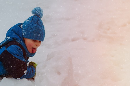 little boy licking snow in winter nature, winter playの写真素材
