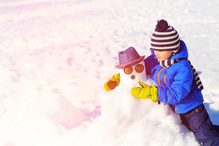 little boy with snowman in winter nature, kids winter playの写真素材