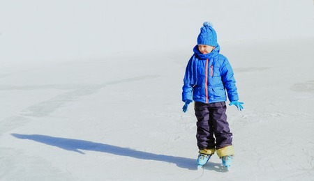 cute little boy learning to skate in winter natureの写真素材
