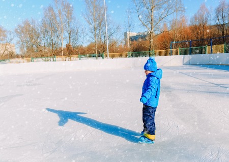 cute little boy learning to skate in winter snowの写真素材