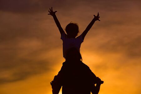 silhouette of father and happy son play on sunset sky