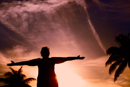 Silhouette of happy senior woman at sunset tropical beach- active retirement conceptの写真素材