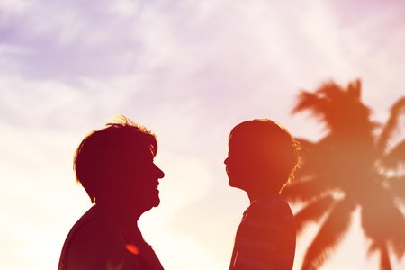 Silhouette of happy grandmother and little grandson at tropical beach, active retirementの写真素材