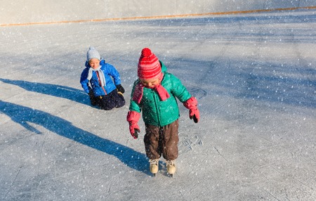 little girl and boy larning to skate in winter nature, kids winter sportの写真素材