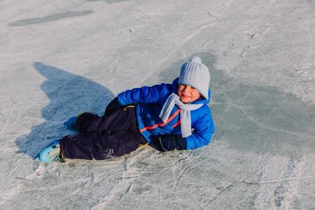 cute little boy learning to skate in winter snowの写真素材